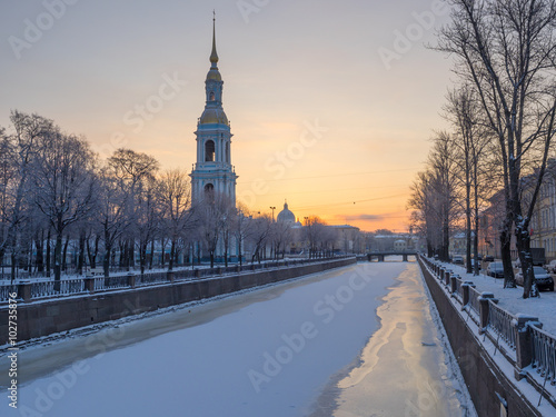 St. Petersburg in the winter. Frozen Griboyedov Canal, St. Nicholas Naval Cathedral bell tower and architecture on its banks against the backdrop of a frosty dawn