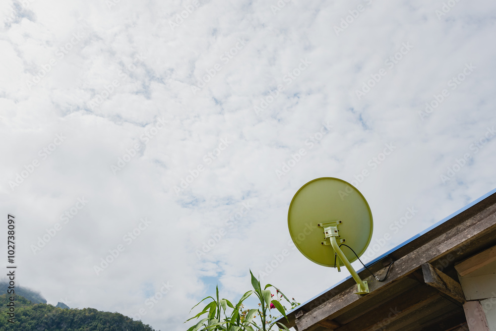 Green satellite dish on the roof with clouds background