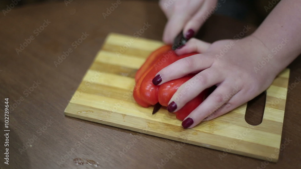 Close-up a hands of a young woman chopping vegetables on a wooden board. Close-up a hands of a young woman chopping vegetables on a wooden board.