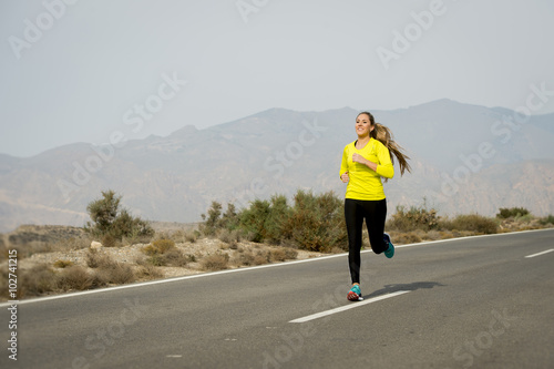 young attractive sport woman running on desert mountain asphalt road