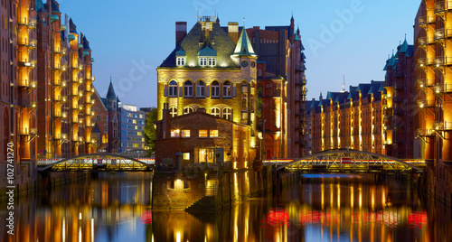 Old Speicherstadt in Hamburg illuminated at night. Sunset backgr