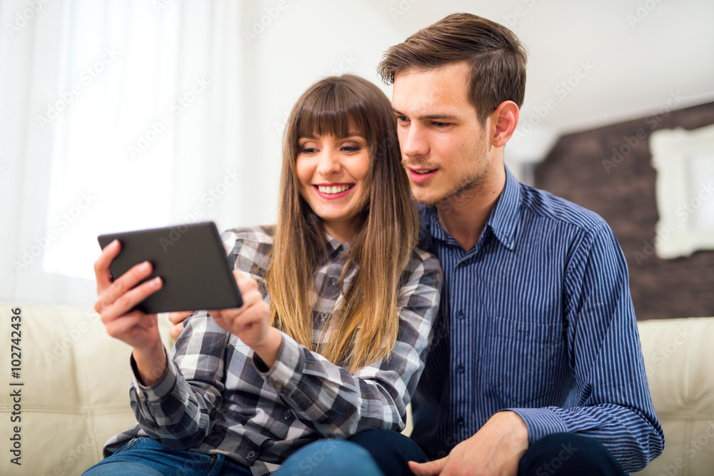 Attractive couple using tablet together on sofa at home. Attractive couple using tablet together on sofa at home.