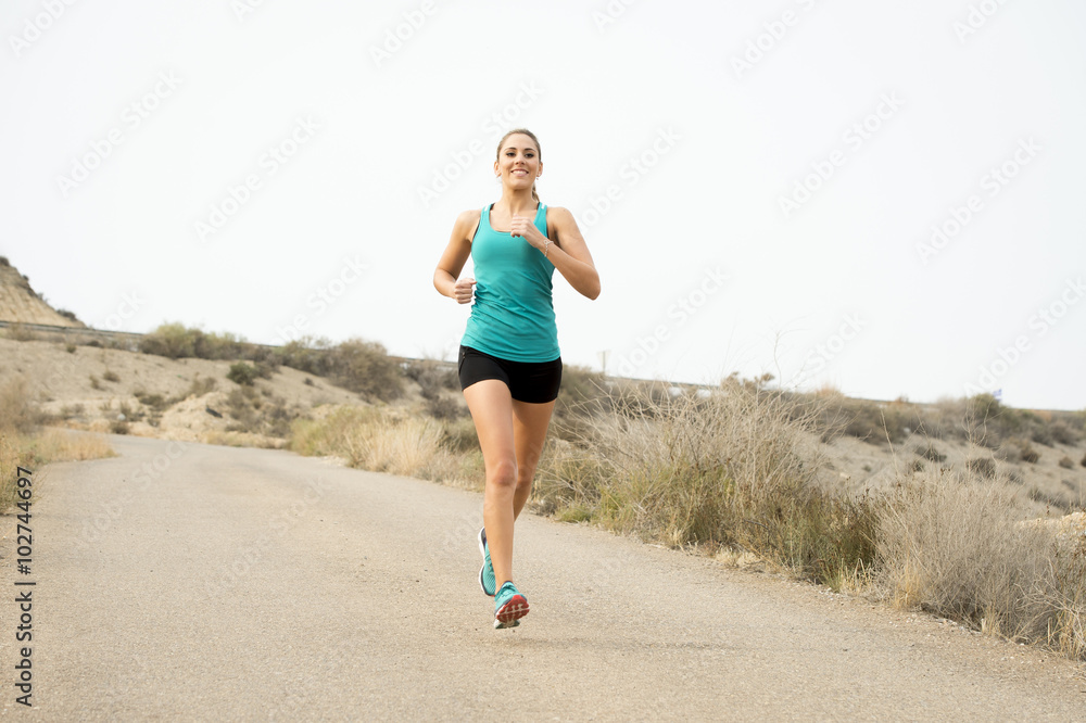 sport woman running on asphalt dirty road with dry desert landscape background training hard