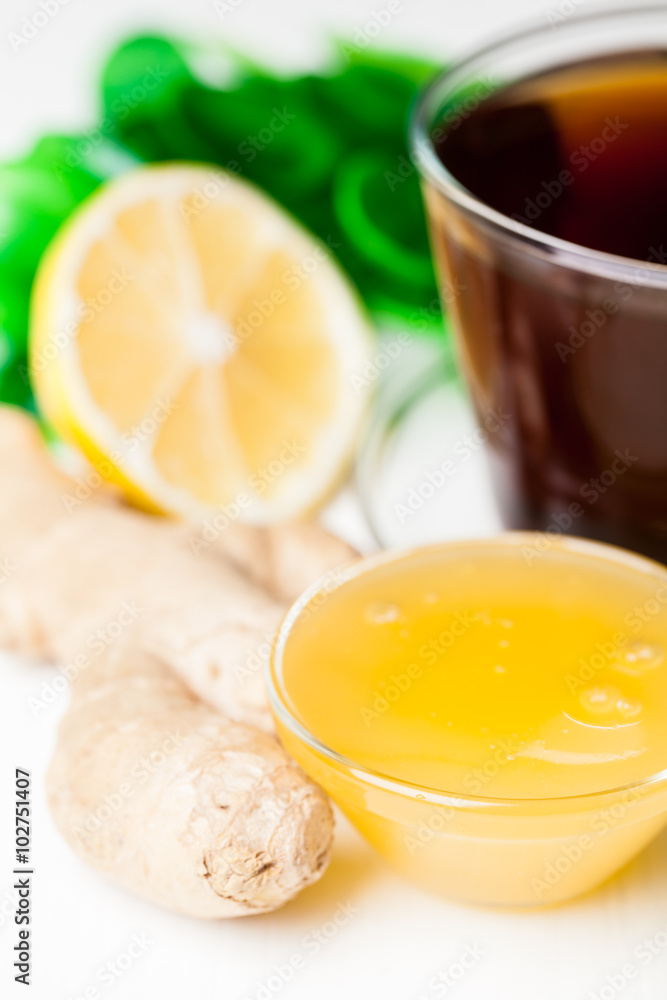 Cup of ginger tea with honey and lemon on white table Cup of ginger tea with honey and lemon on white table