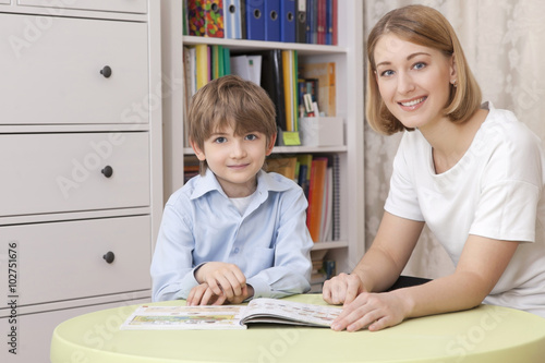 teacher with student sitting at the table with the textbook