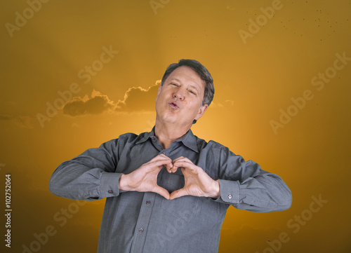 man gives a kiss in the air and shows heart sign with hands photo