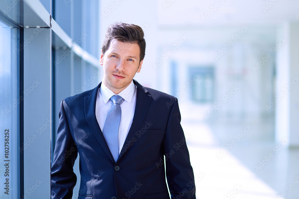 Portrait of businessman standing near window in office Portrait of businessman standing near window in office