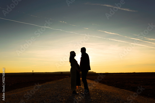 Silhouette of a pregnant woman at sunset with his husband.