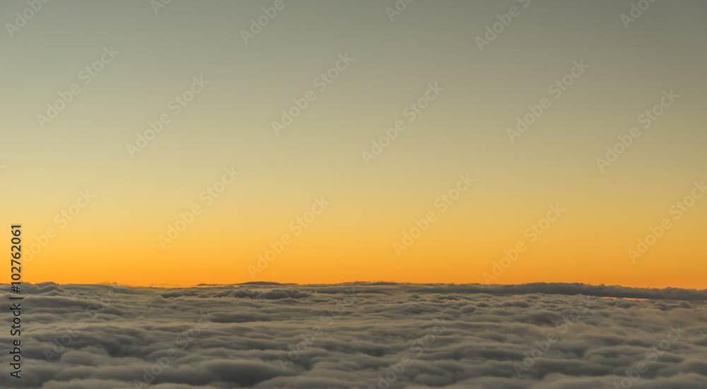 A view form passanger plane's window on the sun setting above the cloud level.