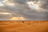 People on camels in the Sahara desert at sunset background