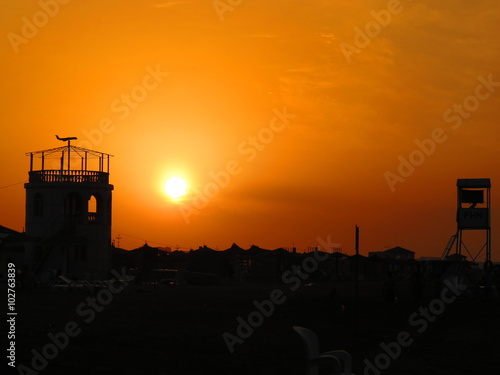 sunset, orange sky and building silhouettes at the beach
