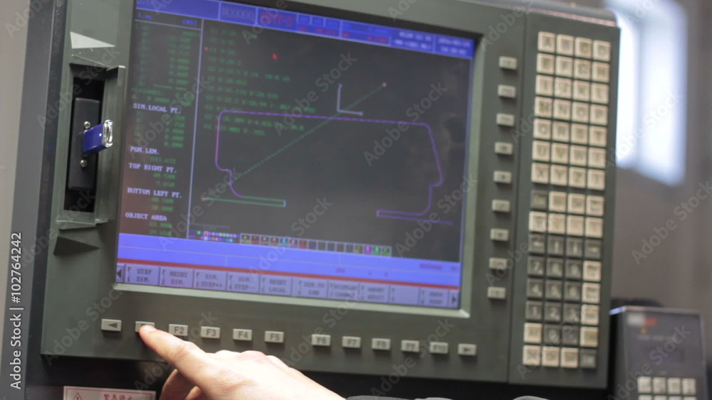 Operator working with control panel of CNC machining centerchanging numbers Operator working with control panel of CNC machining centerchanging numbers