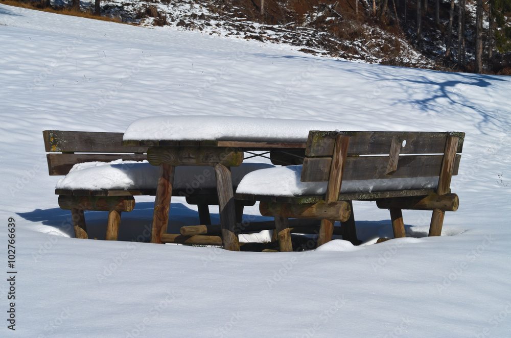 Pic-nic bench and table covered by snow during the winter in the Italian Alps
