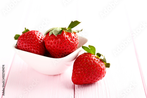 Ripe red strawberry on a pink wooden table