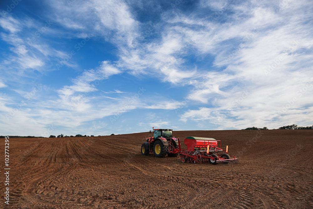 Obraz premium Farmer with tractor seeding crops at field