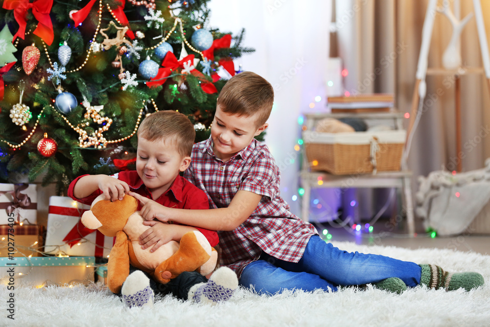 Two cute small brothers with teddy bear on Christmas tree background Two cute small brothers with teddy bear on Christmas tree background