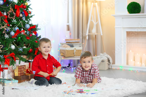 Two cute small brothers playing on Christmas tree background