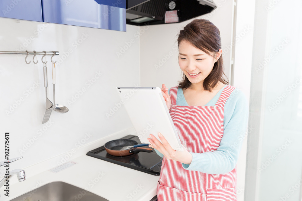 タブレットを見ながら料理をする女性 タブレットを見ながら料理をする女性