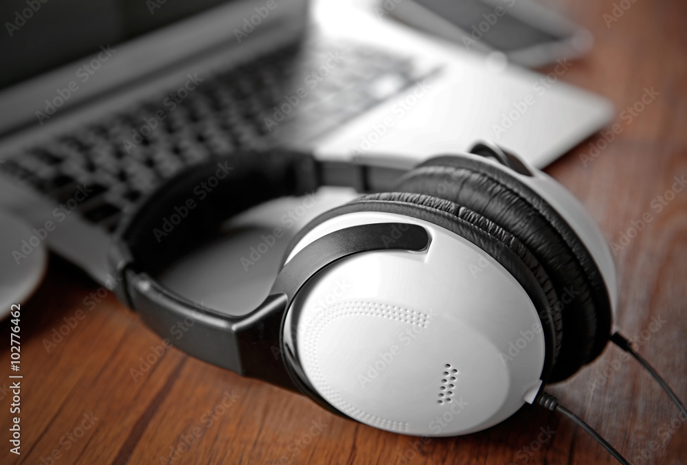 Headphones and laptop on wooden table closeup Headphones and laptop on wooden table closeup