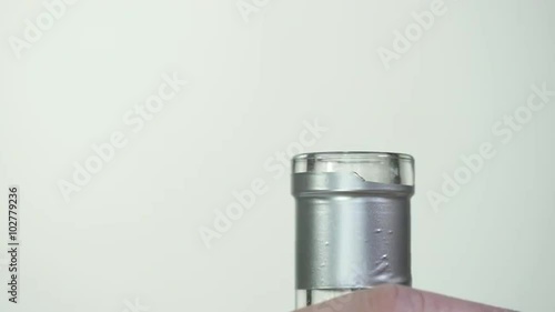 Close up on a hand removing and reinserting the cap on a liquor bottle with a silver foil. photo