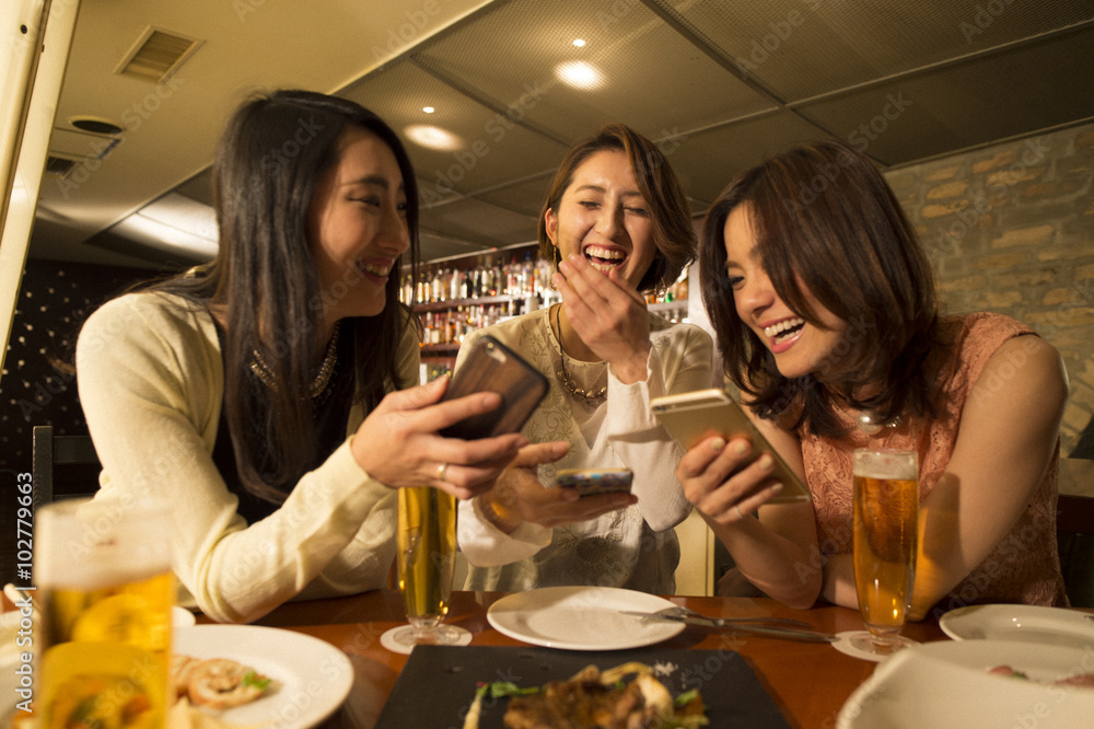 Three women are laughing while looking at the smartphone Three women are laughing while looking at the smartphone