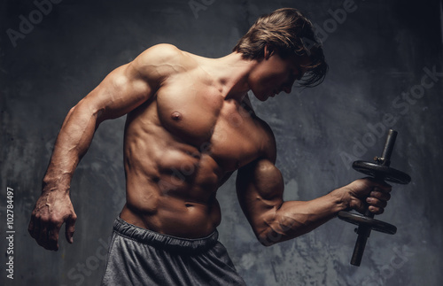 Shirtless muscular man doing biceps workout.