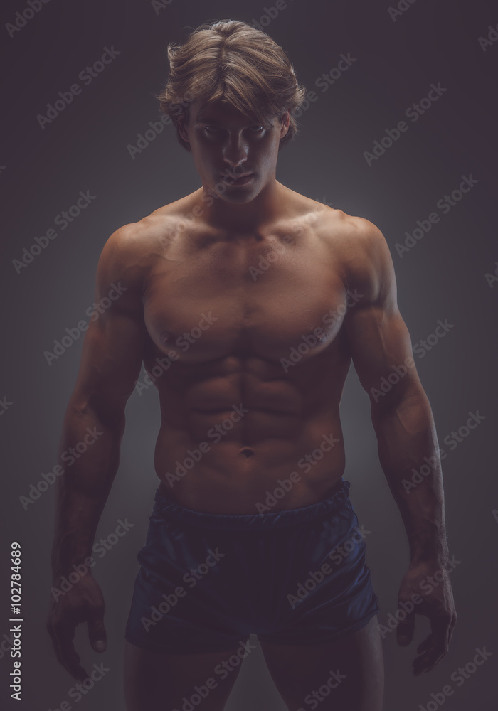 Man in shorts posing in a deep shadows. Man in shorts posing in a deep shadows.