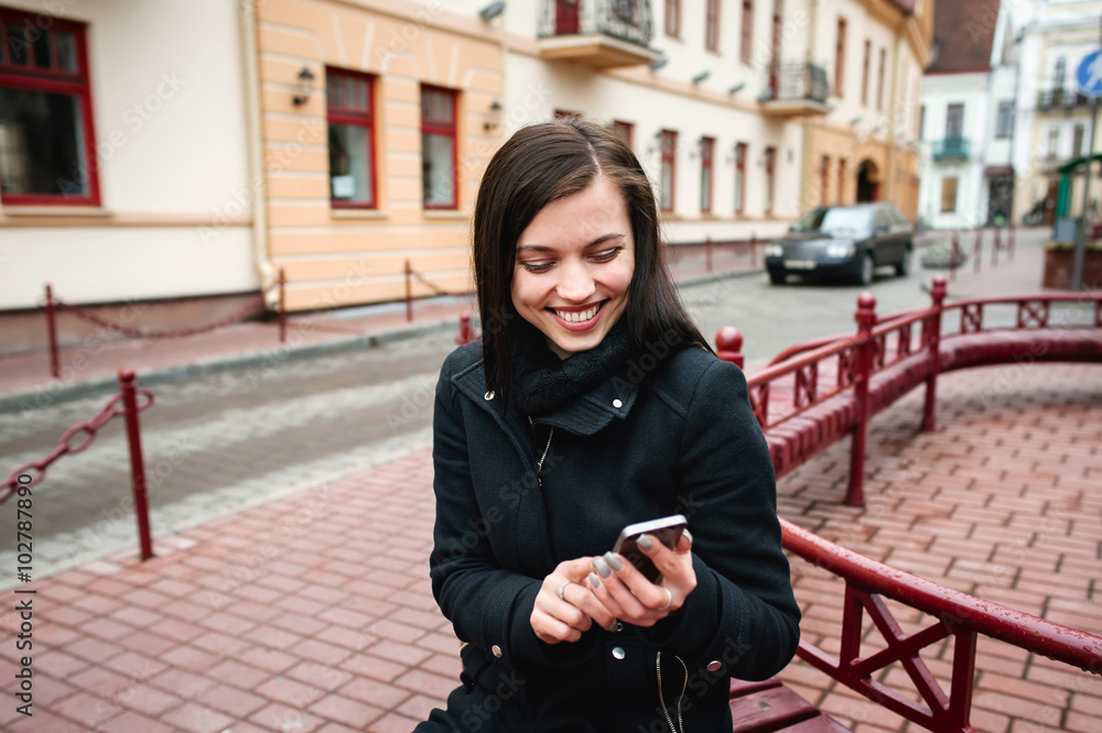 young attractive cheerful woman using phone on the street in the