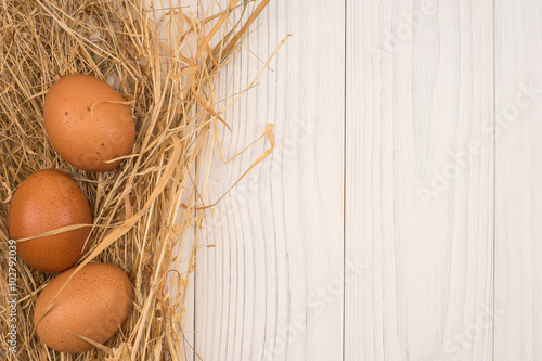 Eggs with straw on wooden background with copy space