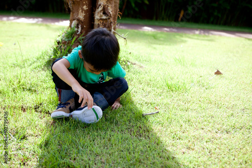 Adorable little boy sitting under tree.