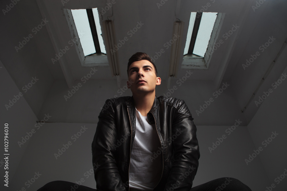 below view of young man in leather jacket posing seated below view of young man in leather jacket posing seated