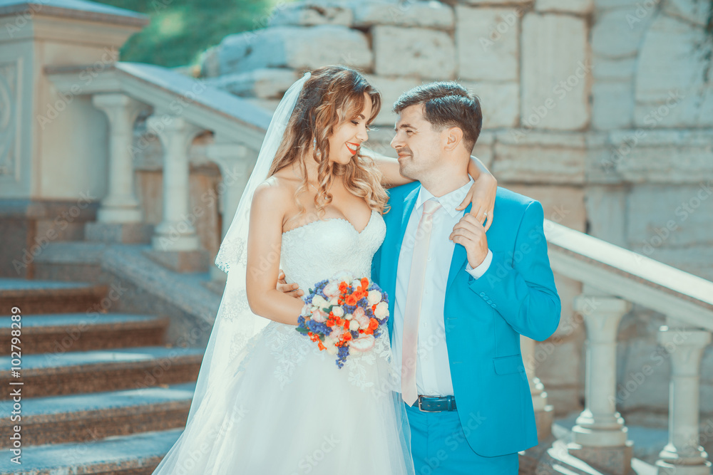 Naklejka premium Newlyweds standing on stairs, looking at each other and smiling
