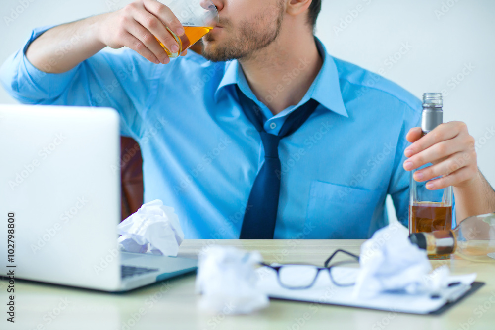Fototapeta premium Drunk man drinking alcohol while working