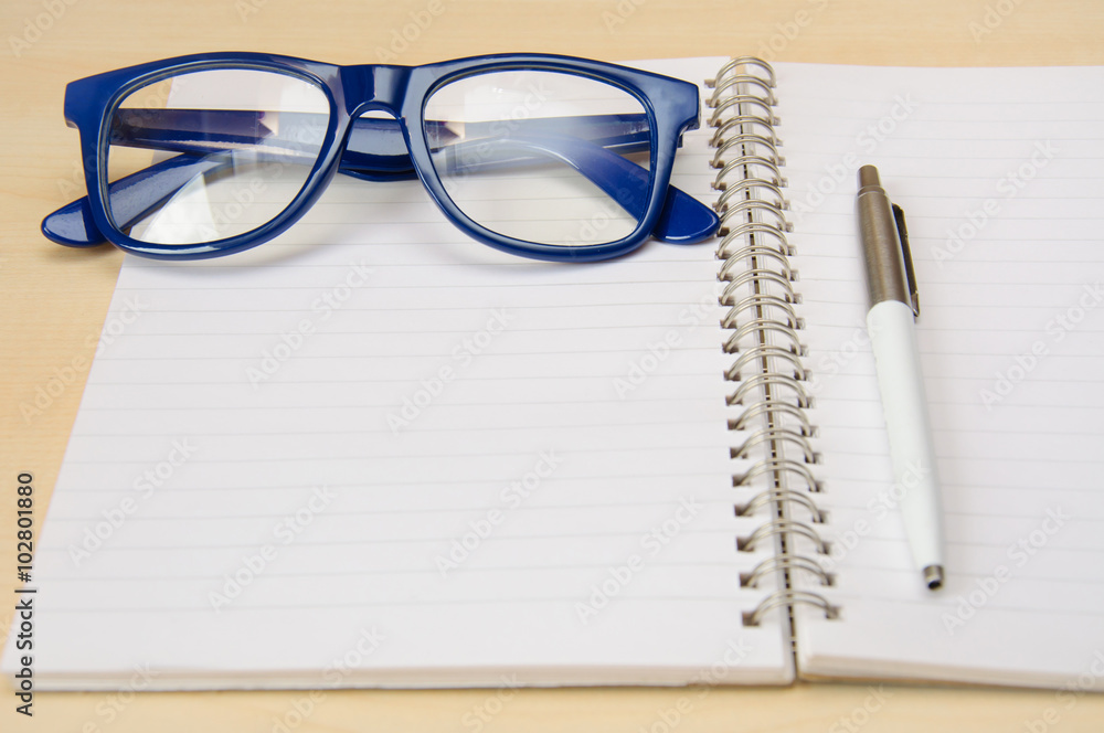 Blue frame eye glasses and empty notebook Blue frame eye glasses and empty notebook