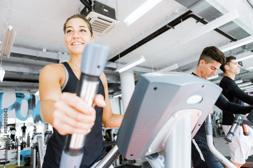 Fototapeta premium Young fit woman using an elliptic trainer