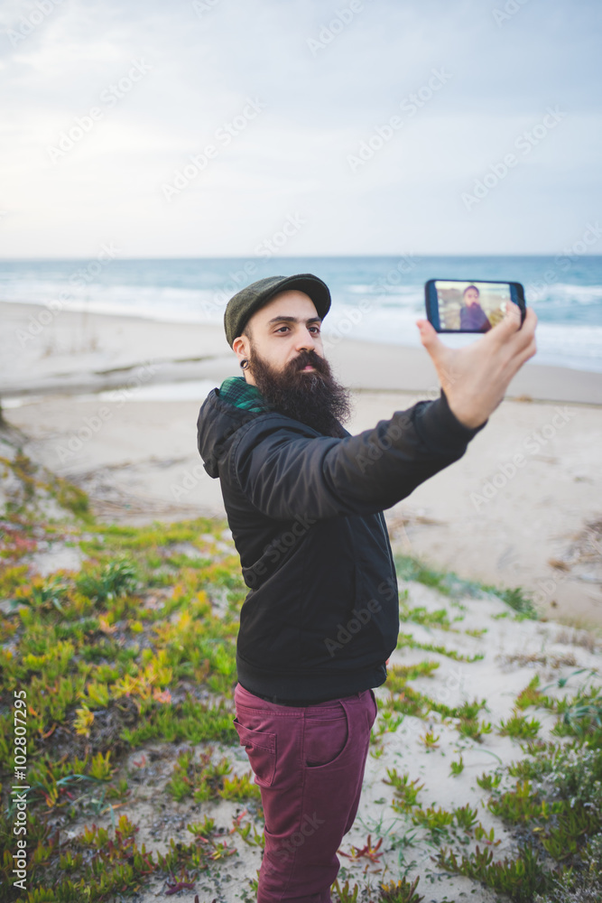 Knee figure of young handsome caucasian bearded man holding a sm Knee figure of young handsome caucasian bearded man holding a sm