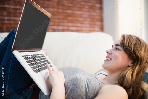 Pretty woman lying on the couch using her laptop