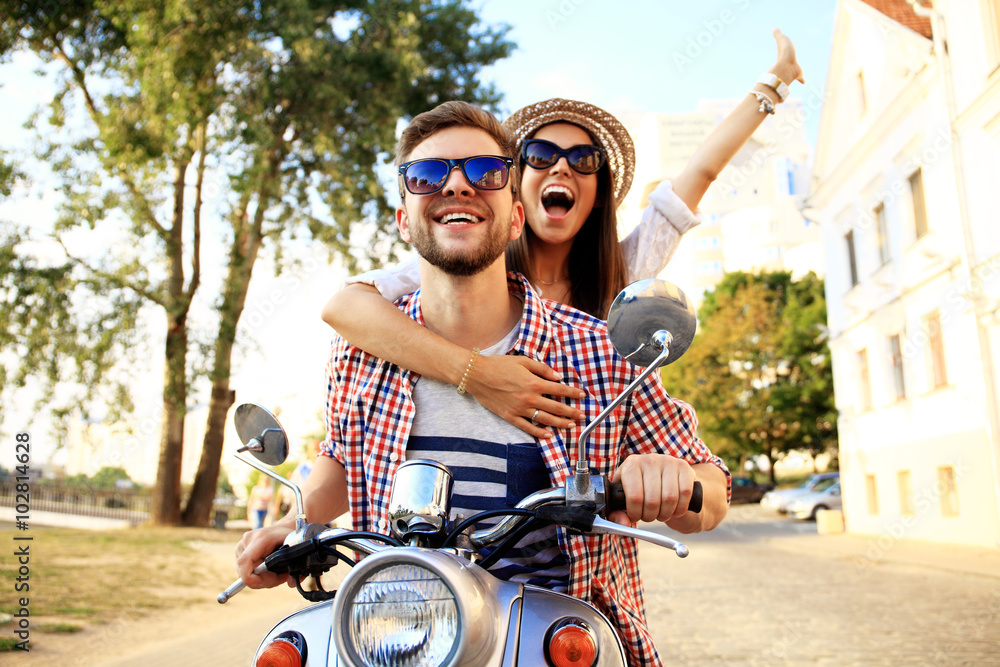 Portrait of happy young couple on scooter enjoying road trip - obrazy, fototapety, plakaty 