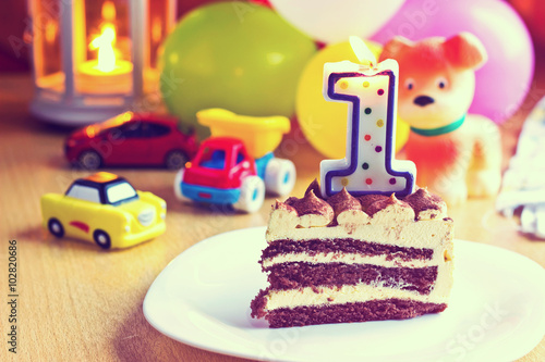 Baby boy first birthday party. Focus on cake with blurred multicolored background. Image with vintage filter