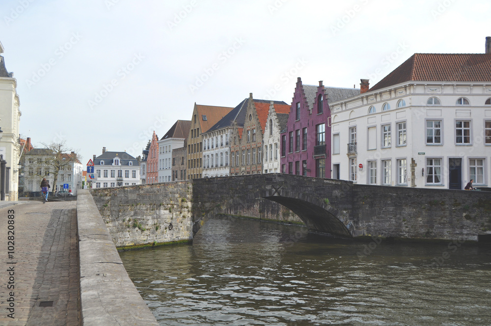 Panoramic view along one of the many canals in Bruges Belgium flanked by characteristic old buildings Panoramic view along one of the many canals in Bruges Belgium flanked by characteristic old buildings