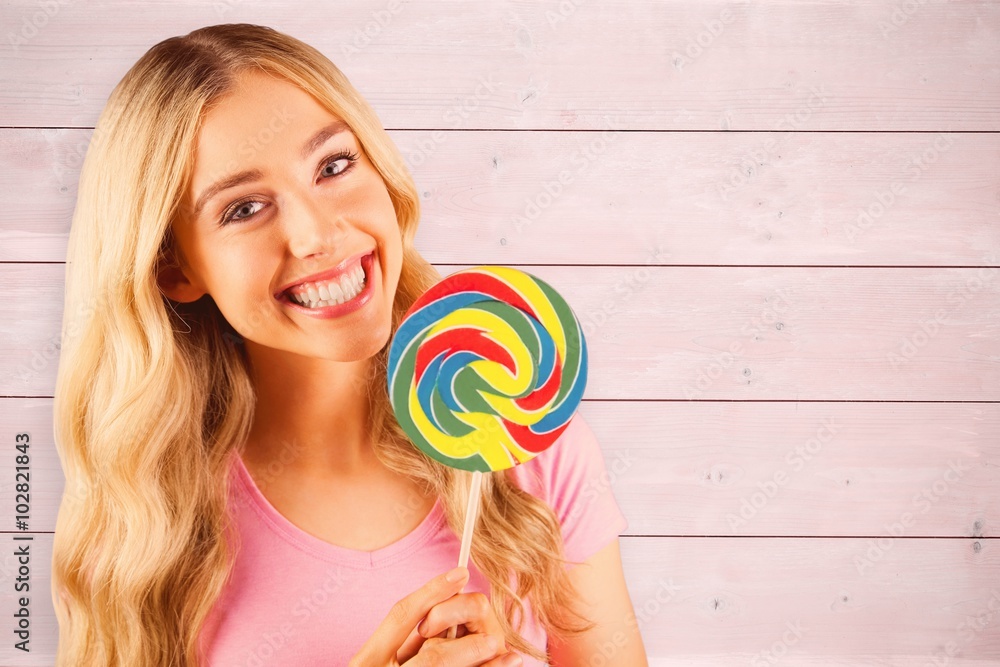 Composite image of a beautiful woman holding a giant lollipop 