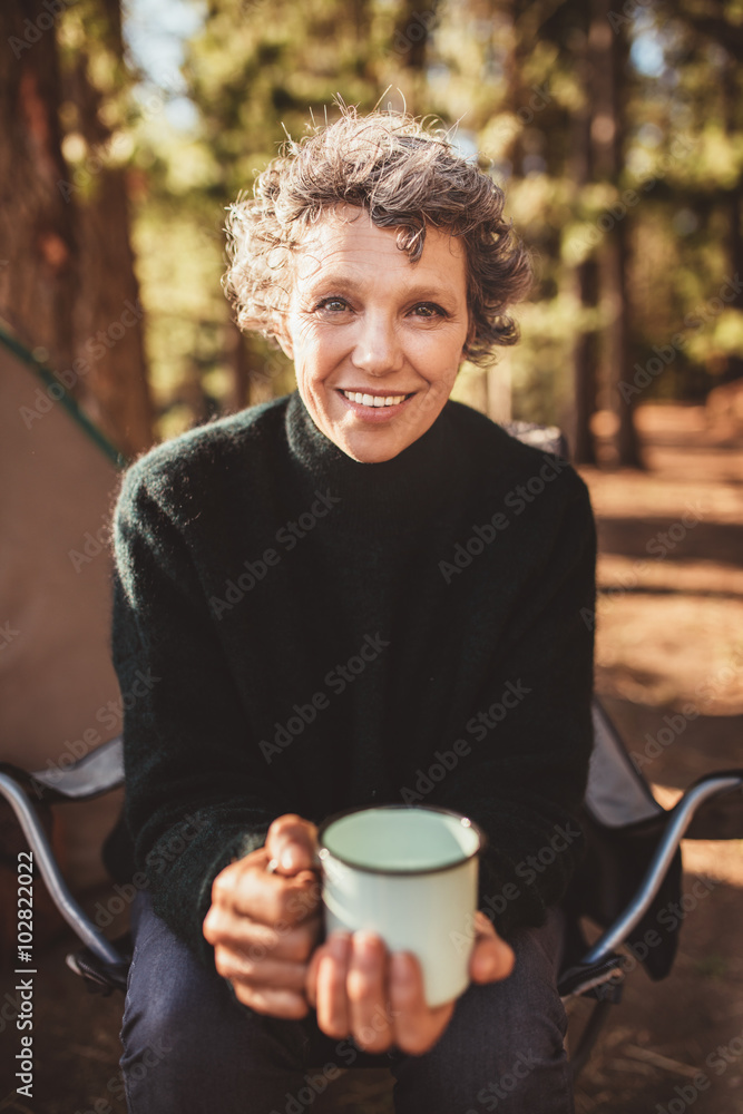 Senior woman sitting outside the tent with a cup of coffee Senior woman sitting outside the tent with a cup of coffee