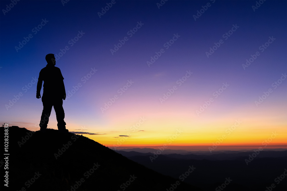 Silhouette of man standing on the top of mountain to enjoy colourful sky Silhouette of man standing on the top of mountain to enjoy colourful sky