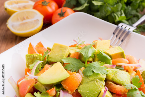 Fresh avocado Salad  with tomatoes, purple onion on the white dish. Healthyt food concept photo