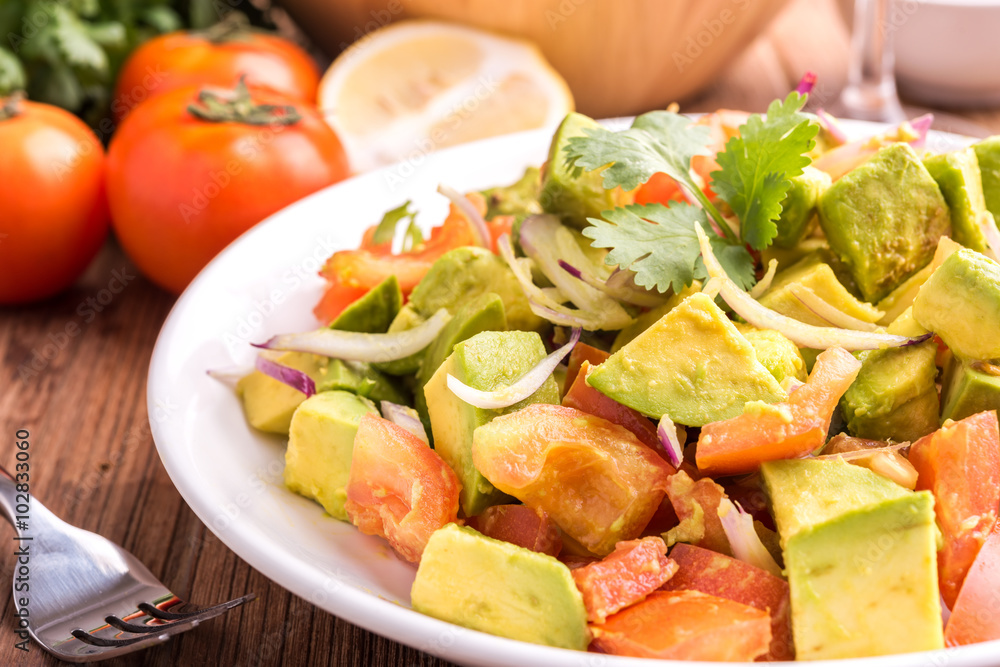 Fresh avocado Salad with tomatoes, purple onion on the white dish. Healthyt food concept Fresh avocado Salad with tomatoes, purple onion on the white dish. Healthyt food concept