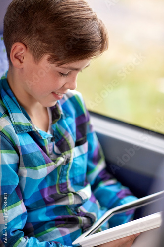 happy boy with tablet pc in travel bus or train