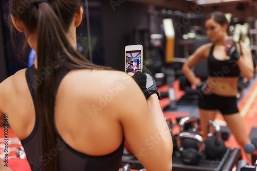 woman with smartphone taking mirror selfie in gym © Syda Productions
