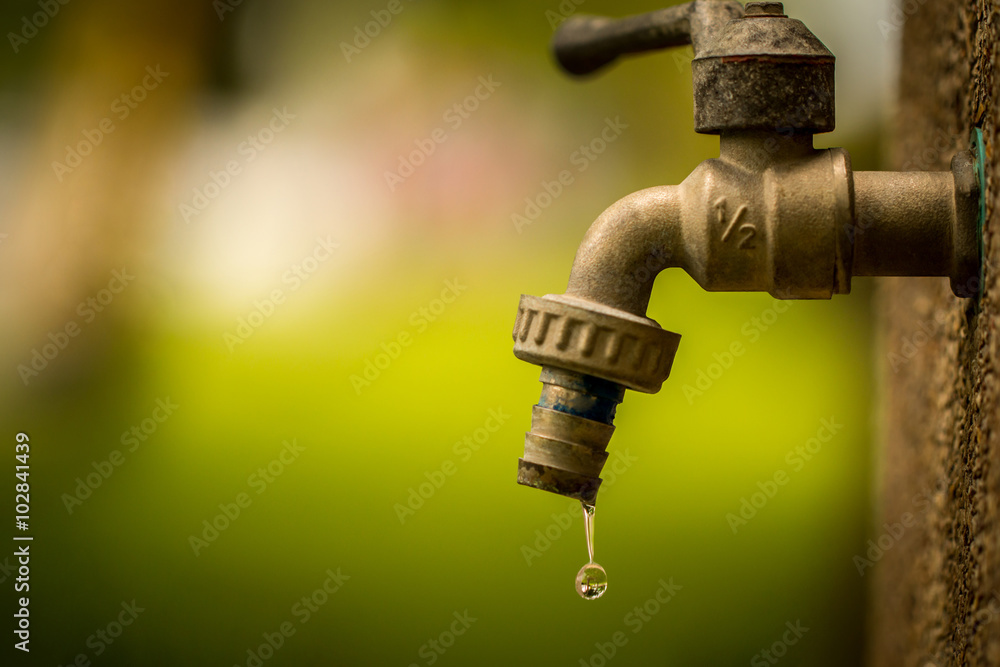 Water tap in park. Old and worn out, causing a water drop as consumption Resource.
Consumption of water.