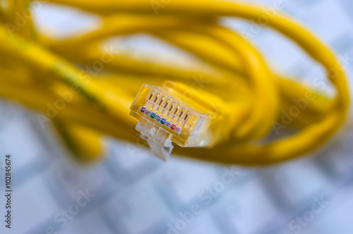 Macro of a yellow network cable in front of a computer keyboard photo
