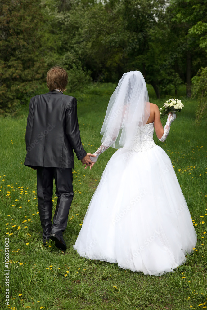 bride and groom walking on the grass with flowers bride and groom walking on the grass with flowers